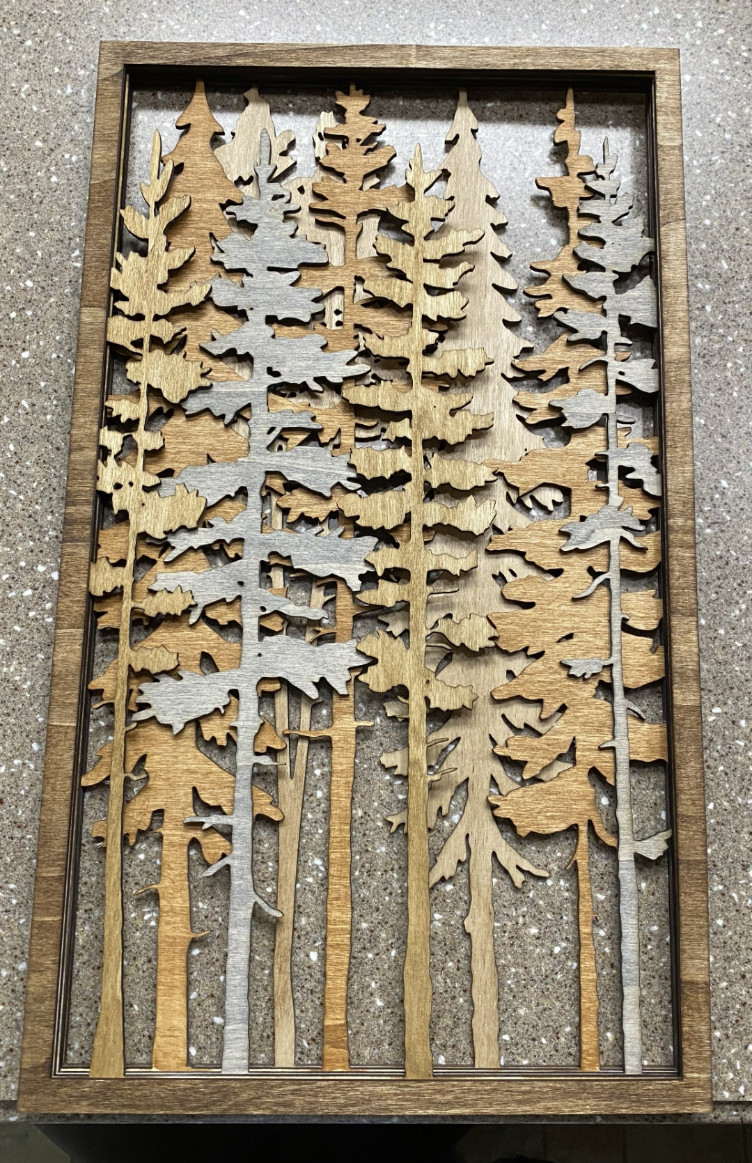Layered laser-cut wood forest scene in a dark wood frame